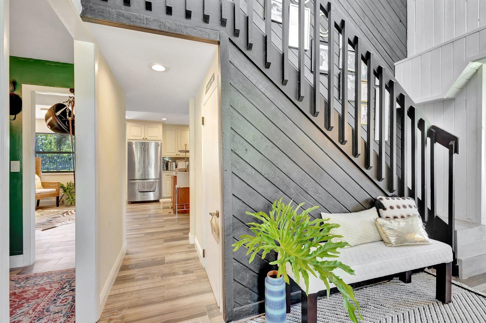 A hallway features a staircase with diagonal dark wood paneling and a white bench — 5446 Reynolds Road, Lake Worth FL 33449, LAKE WORTH, FL