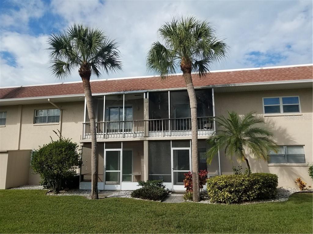 The exterior of a two-story apartment building features screened-in balconies and two tall palm trees — 2727 75TH STREET W UNIT 7A3, BRADENTON, FL