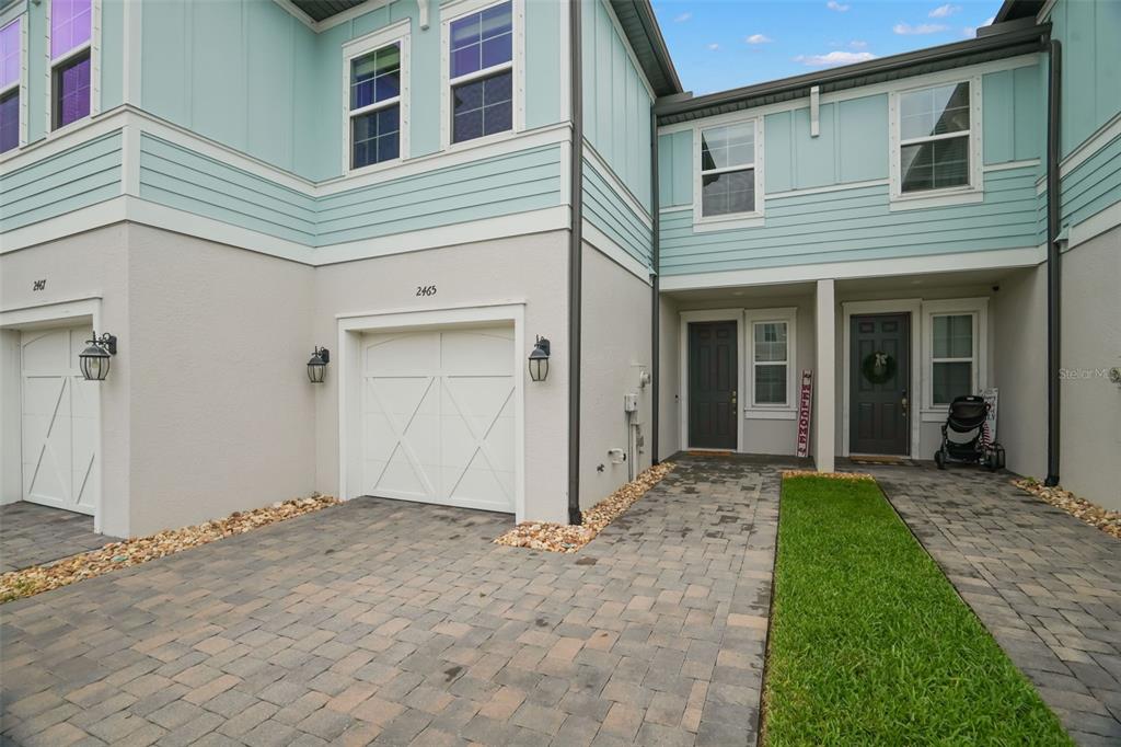 The exterior of a two-story townhouse features light blue siding, white stucco, and a paved driveway — 2465 FOGGY CREEK CIRCLE, CLEARWATER, FL
