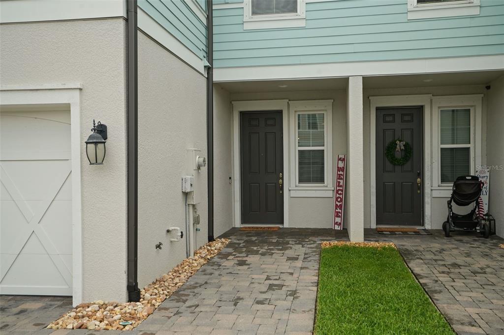 The exterior view shows two adjacent townhome entrances with dark doors and a paved walkway — 2465 FOGGY CREEK CIRCLE, CLEARWATER, FL