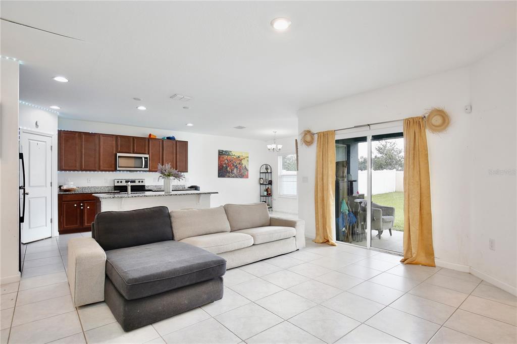 A living room with tile floors and a sectional sofa opens to a kitchen area — 490 TAFT DRIVE, DAVENPORT, FL