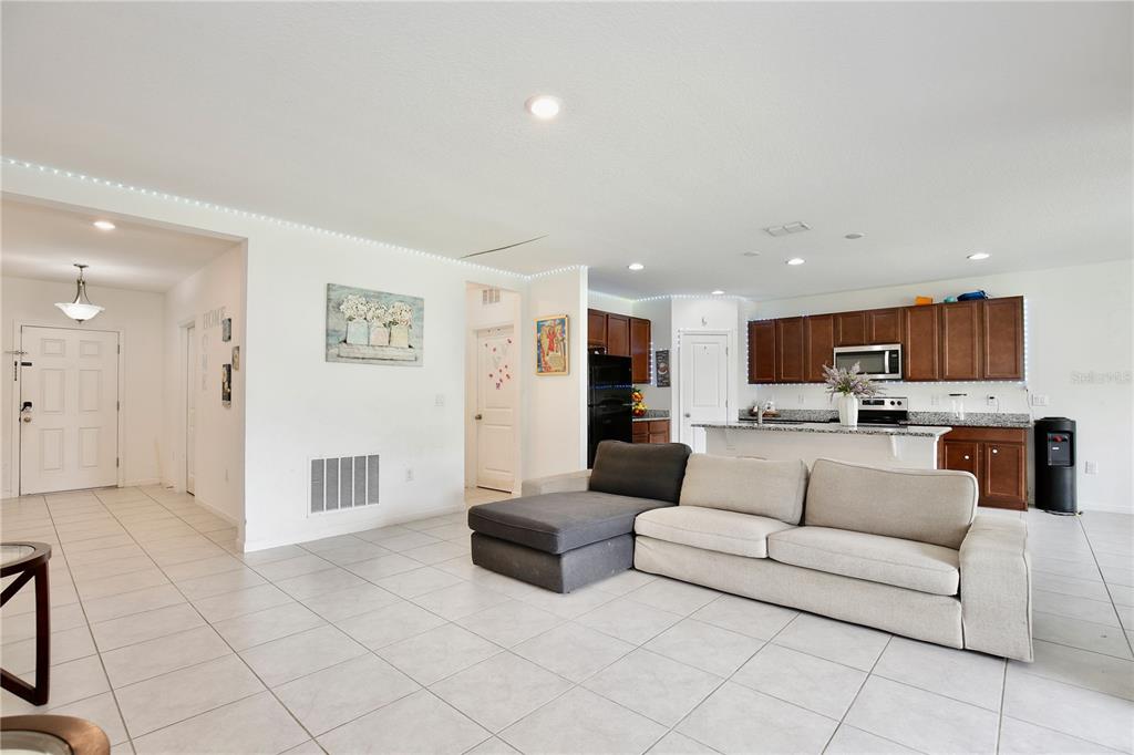 An open-concept living room features light tile flooring, a sectional sofa, and a kitchen area — 490 TAFT DRIVE, DAVENPORT, FL