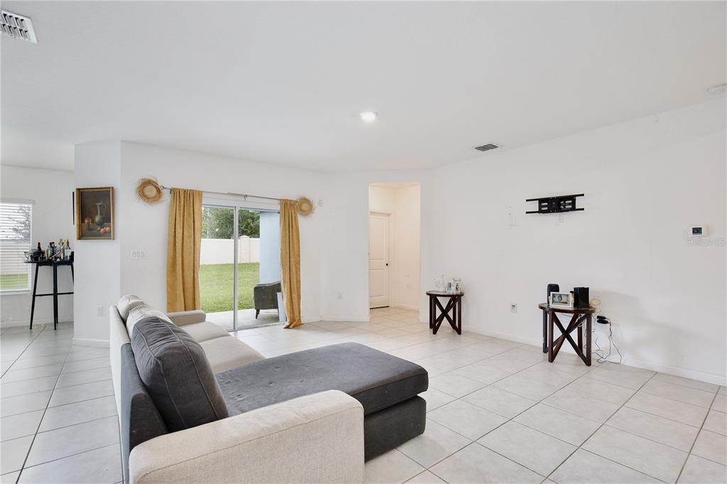 A living room features white walls, tile flooring, a gray sectional sofa, and sliding glass doors — 490 TAFT DRIVE, DAVENPORT, FL