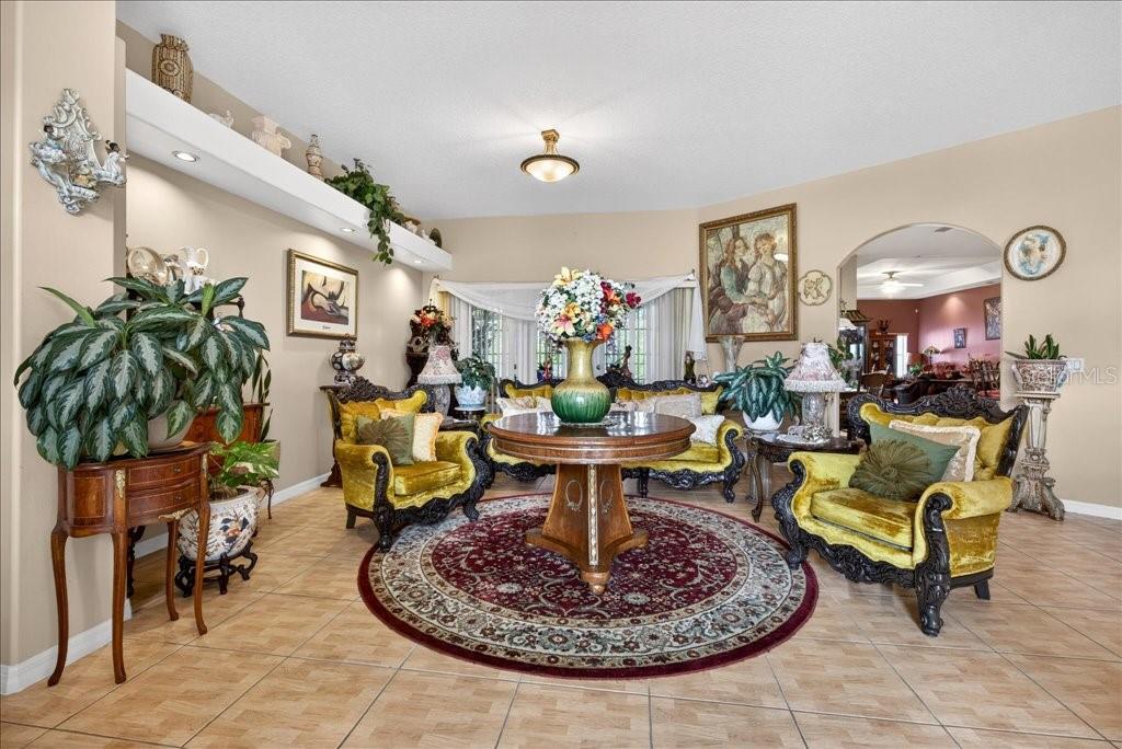 A living room features ornate gold velvet furniture, a round wooden table, and tile flooring — 52 UPSHIRE PATH, PALM COAST, FL