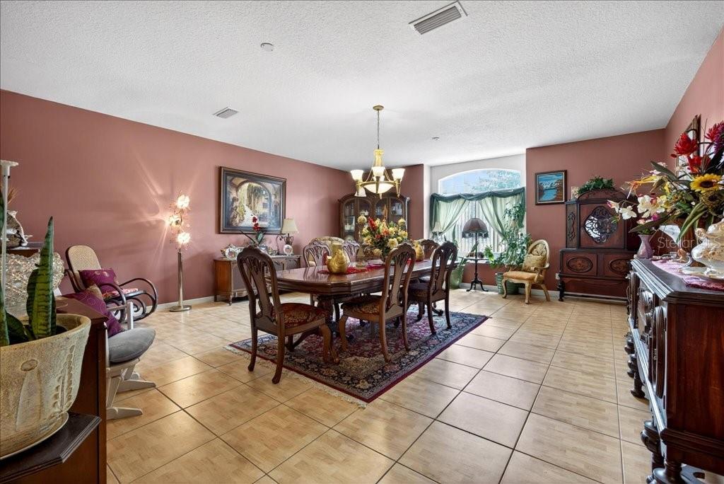 A dining room features a long wooden table, chairs, a chandelier, and tile flooring — 52 UPSHIRE PATH, PALM COAST, FL