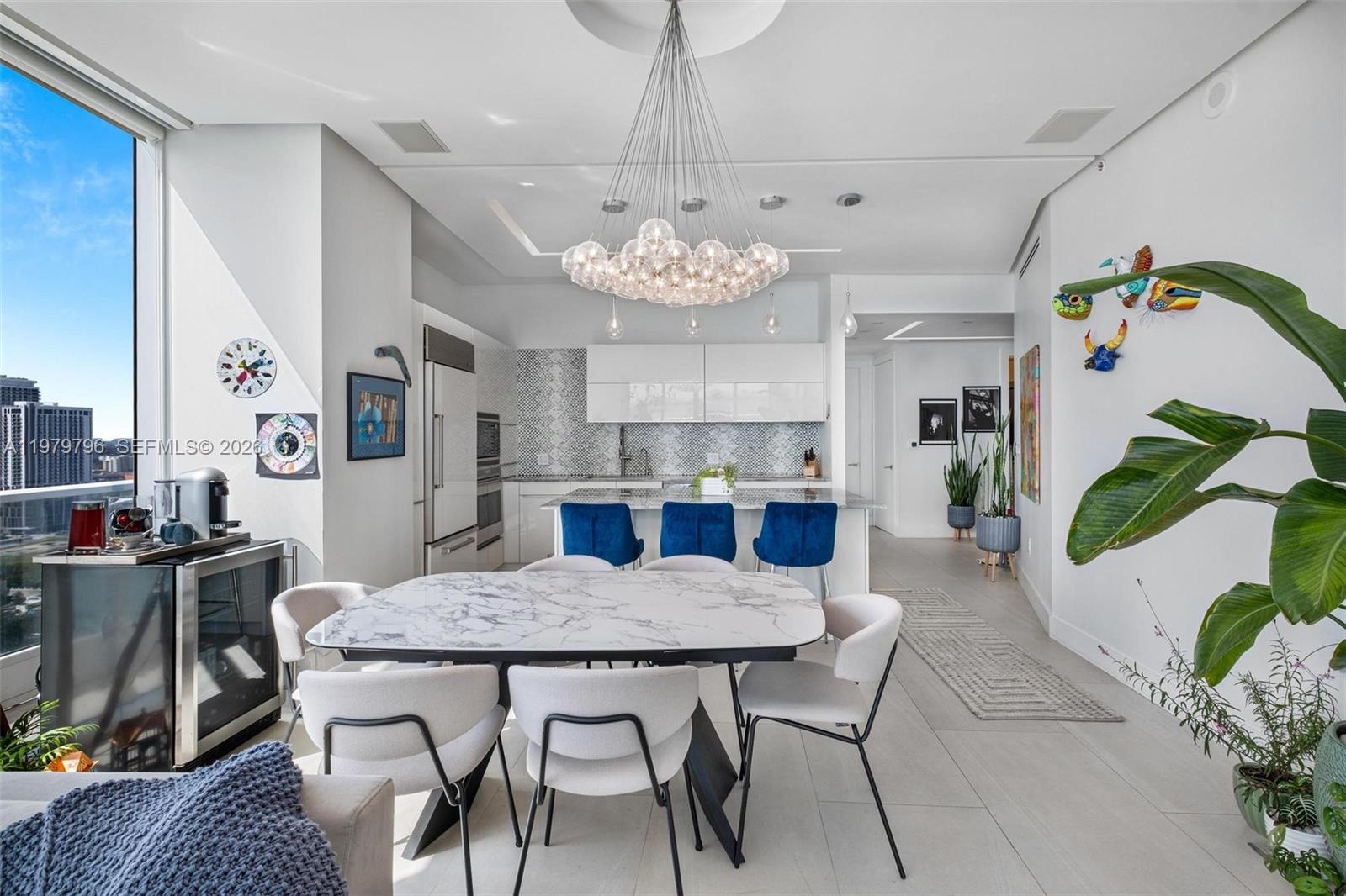 A modern kitchen and dining area features a marble table, blue barstools, and a chandelier — 2020 N Bayshore Dr # 2510, Miami FL 33137, MIAMI, FL