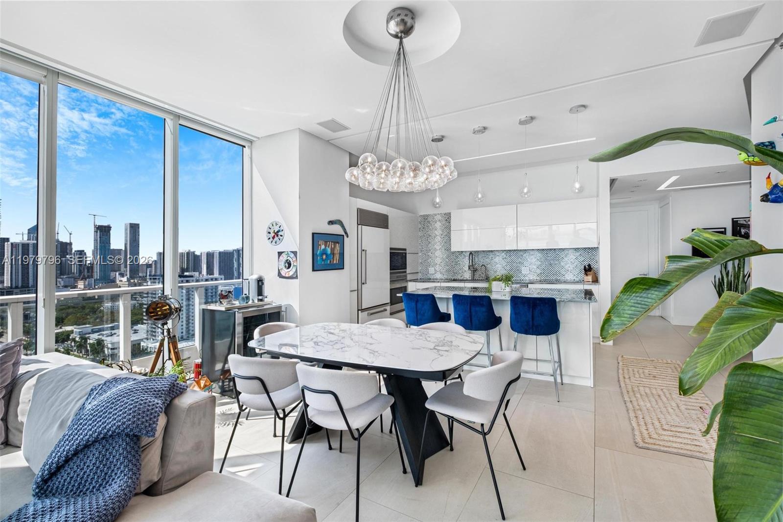 A modern open-concept kitchen and dining area features a marble table, blue stools, and city views — 2020 N Bayshore Dr # 2510, Miami FL 33137, MIAMI, FL