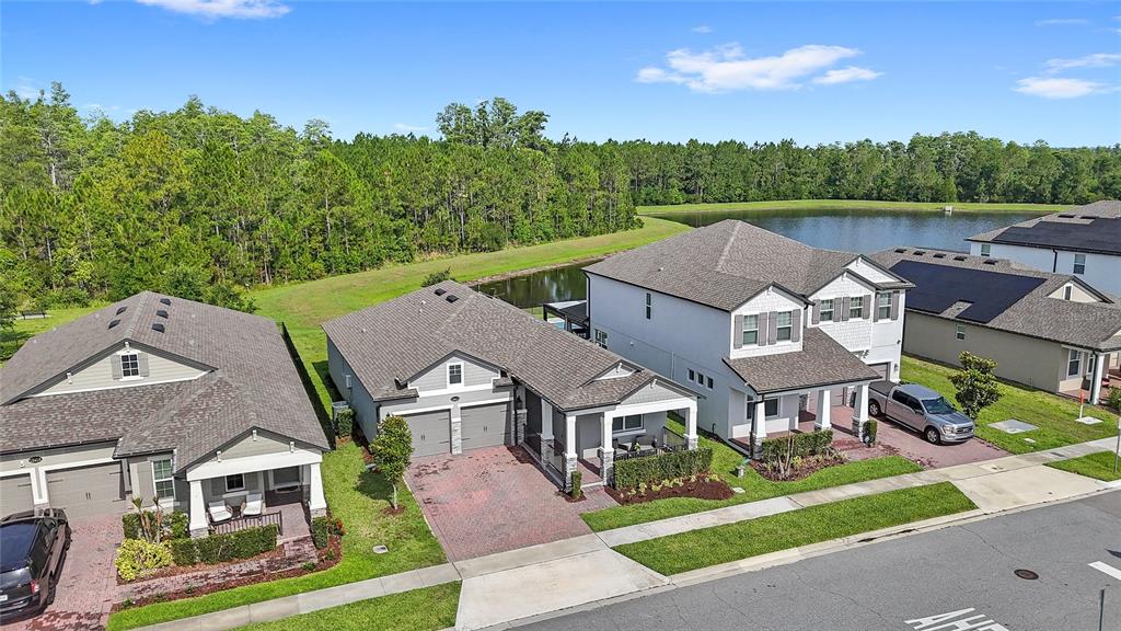 An aerial view shows three suburban houses with driveways and lawns near a pond — 12410 ENCORE AT OVATION WAY, WINTER GARDEN, FL