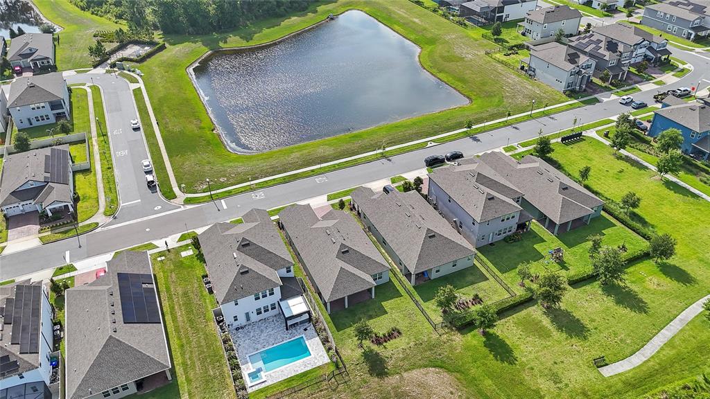 An aerial view shows suburban houses with a central pond and surrounding residential streets — 12410 ENCORE AT OVATION WAY, WINTER GARDEN, FL