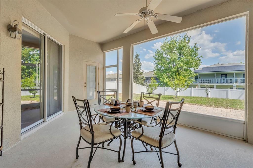 A screened-in patio features a glass dining table, four chairs, and a ceiling fan — 5459 RISHLEY RUN WAY, MOUNT DORA, FL