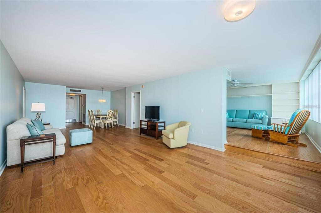 A spacious living and dining area features light blue walls, hardwood floors, and a sunroom — 5130 BRITTANY DRIVE S UNIT 202, ST PETERSBURG, FL