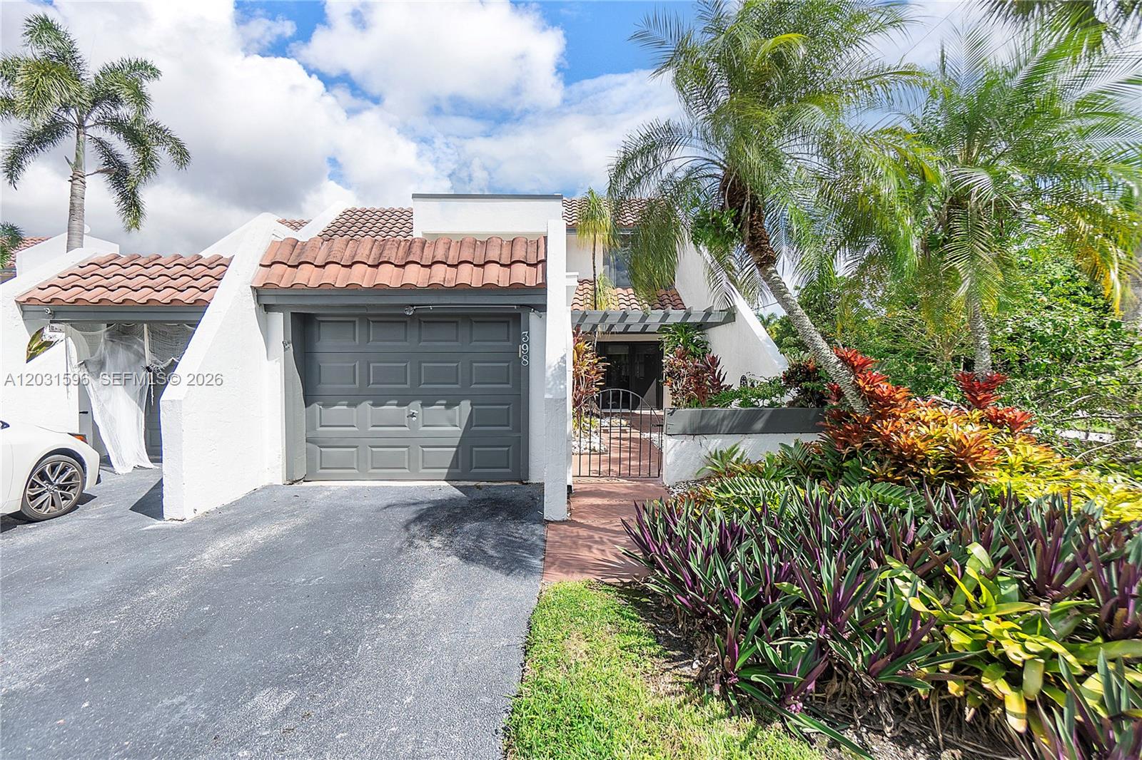A white house with a gray garage, tile roof, and lush landscaping in the front — 398 Fern Dr # 6, Weston FL 33326, WESTON, FL