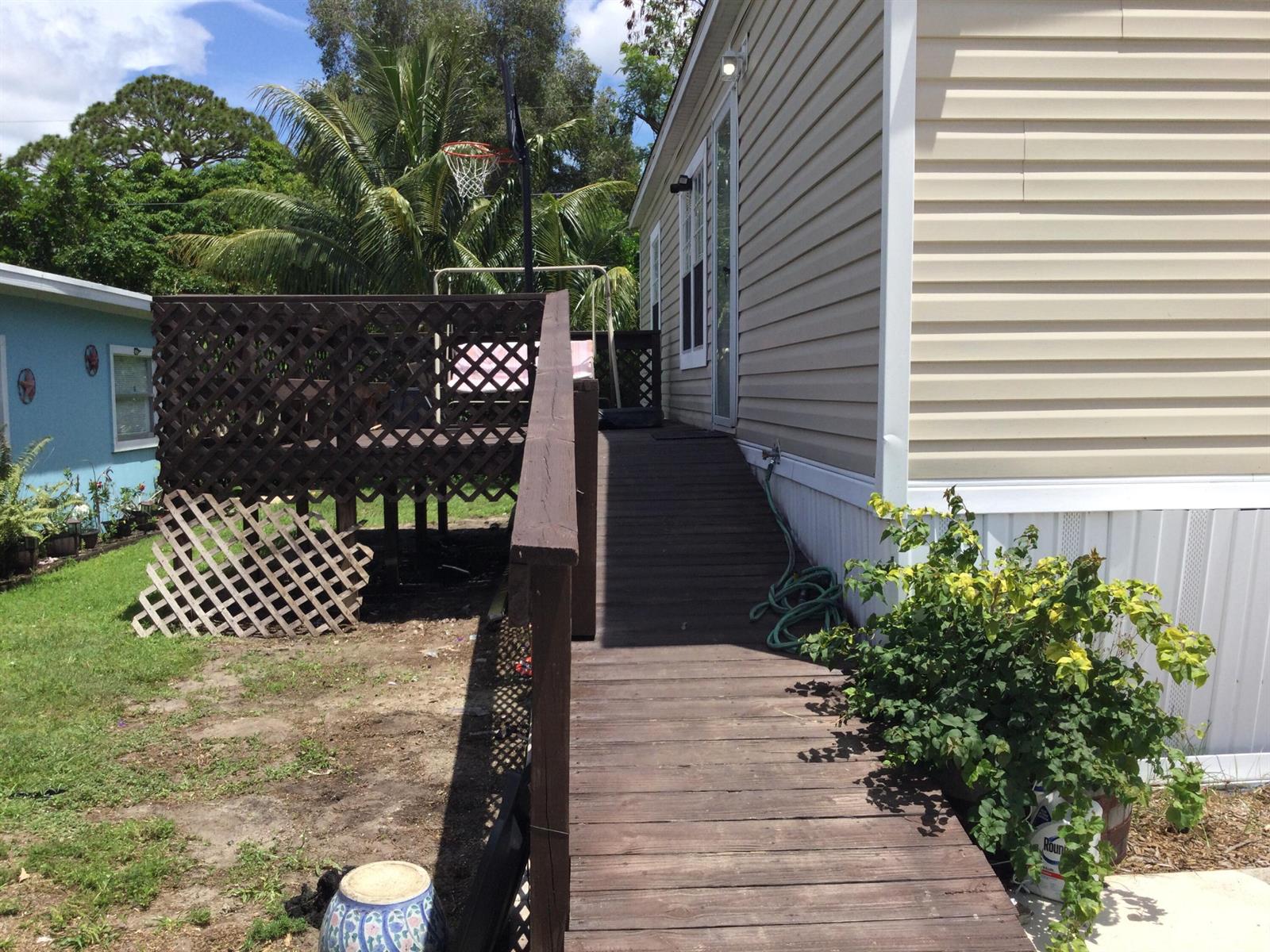 A wooden ramp leads to the side entrance of a beige mobile home — 5000 SE Federal Highway # 82, Stuart FL 34997, STUART, FL