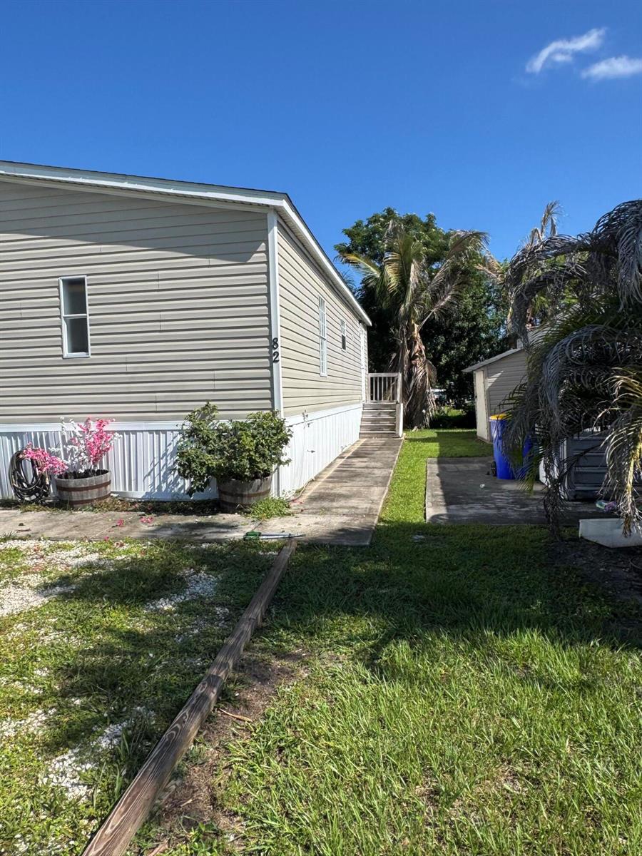 The exterior of a beige manufactured home features a side walkway and a small staircase — 5000 SE Federal Highway # 82, Stuart FL 34997, STUART, FL