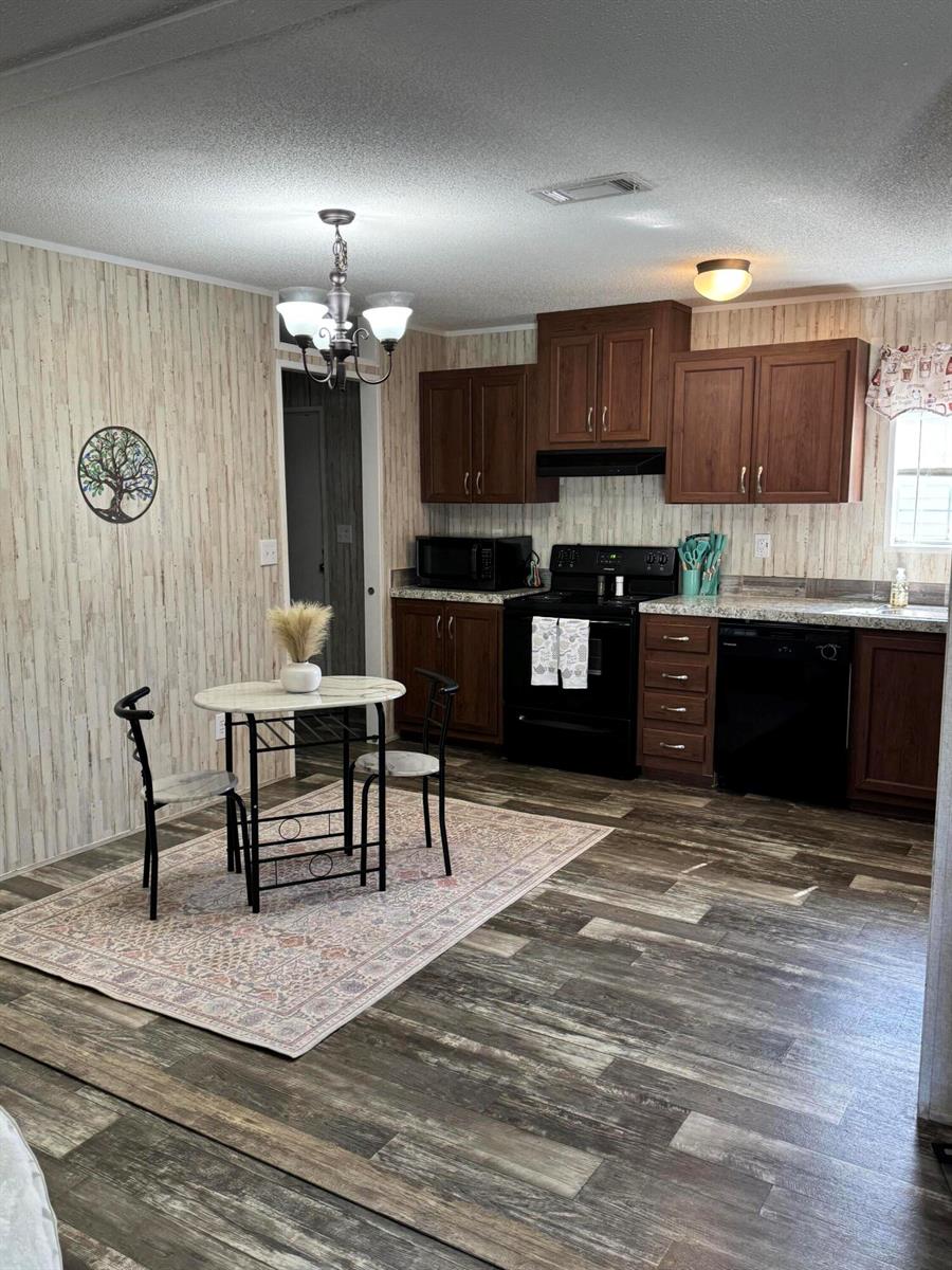 A kitchen and dining area with wood-look flooring, dark wood cabinets, and a small round table — 5000 SE Federal Highway # 82, Stuart FL 34997, STUART, FL