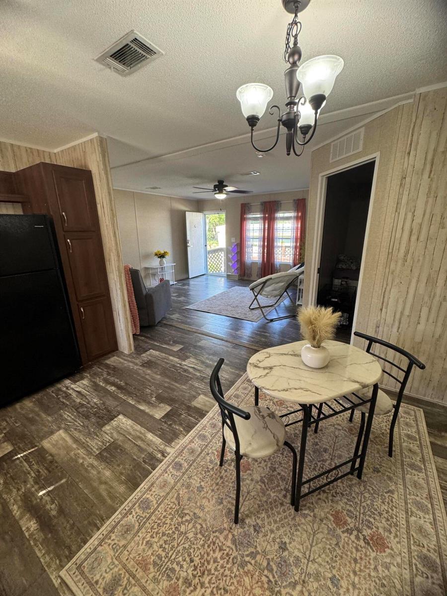 A dining area with a marble-topped table leads into a living room with wood-look flooring — 5000 SE Federal Highway # 82, Stuart FL 34997, STUART, FL
