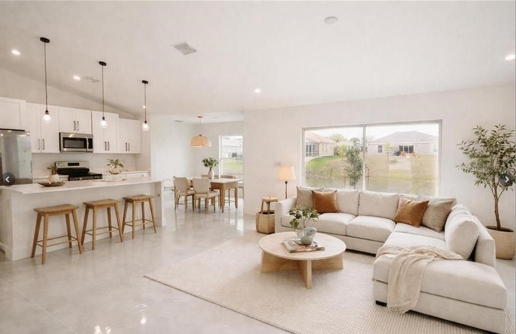 An open-concept living room and kitchen with white cabinetry, a sectional sofa, and tile floors — 2906 NW 22ND AVENUE, CAPE CORAL, FL