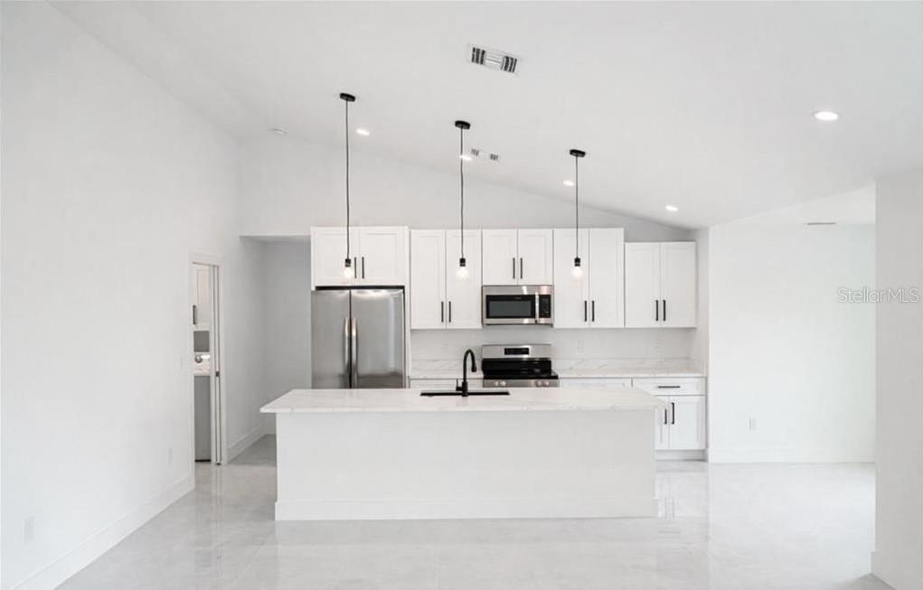 A modern kitchen features white cabinets, stainless steel appliances, and a large central island — 2906 NW 22ND AVENUE, CAPE CORAL, FL