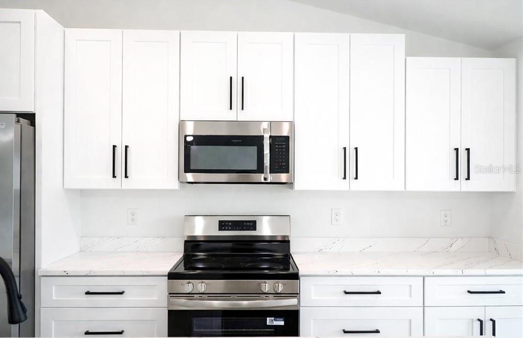 A kitchen features white shaker cabinets, stainless steel appliances, and white marble-patterned countertops — 2906 NW 22ND AVENUE, CAPE CORAL, FL
