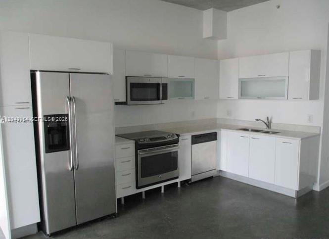 A modern kitchen features white cabinetry, stainless steel appliances, and dark concrete flooring — 133 NE 2nd Ave # 1103, Miami FL 33132, MIAMI, FL