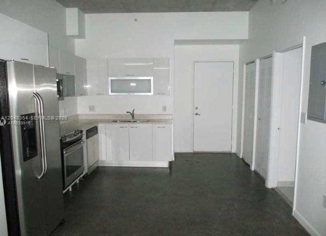 A modern kitchen features stainless steel appliances, white cabinetry, and dark concrete flooring — 133 NE 2nd Ave # 1103, Miami FL 33132, MIAMI, FL