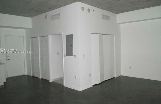 An interior view of a room with white walls, concrete floors, and several closet doors — 133 NE 2nd Ave # 1103, Miami FL 33132, MIAMI, FL