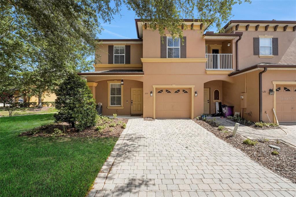 A two-story tan townhouse with a paved driveway, a single-car garage, and a small balcony — 1111 LONG OAK WAY, SANFORD, FL