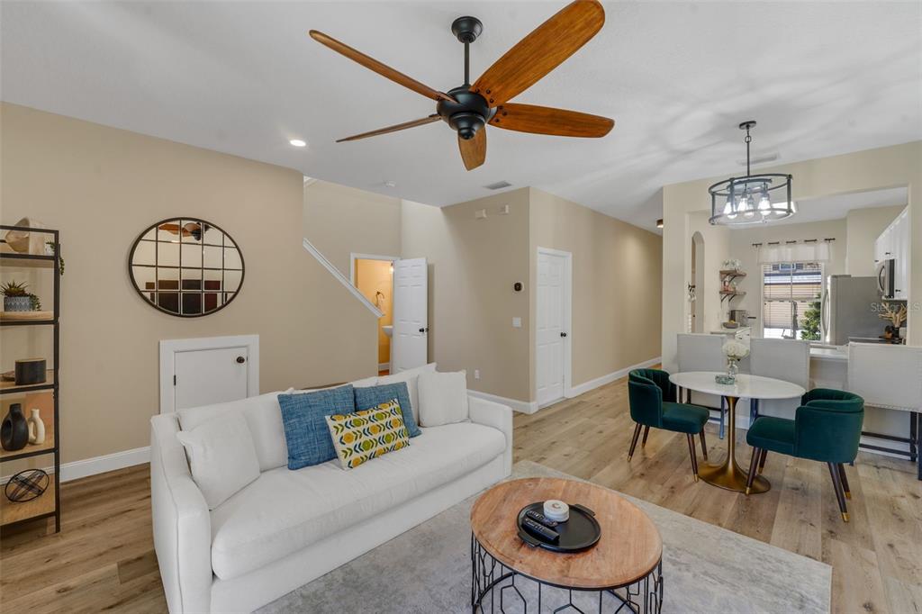 A living room with a white sofa, wood coffee table, and dining area with green chairs — 1111 LONG OAK WAY, SANFORD, FL