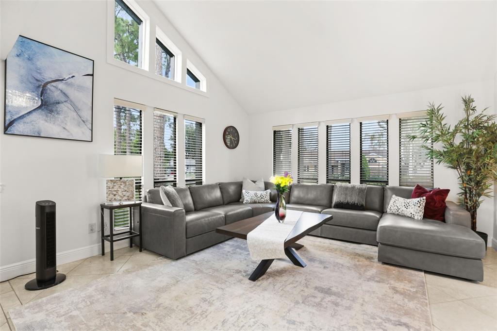 A living room features a grey sectional sofa, a coffee table, and large windows — 9524 BAY VISTA ESTATES BOULEVARD, ORLANDO, FL