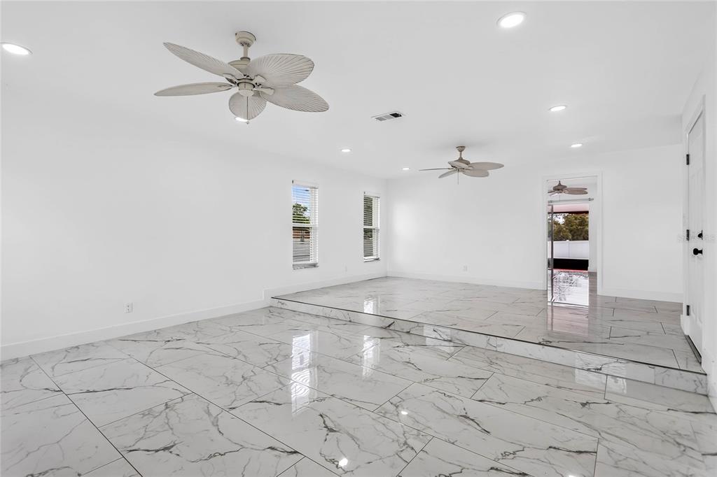 A bright living room features white walls, recessed lighting, ceiling fans, and white marble-look tile — 2327 EVA AVENUE, SPRING HILL, FL