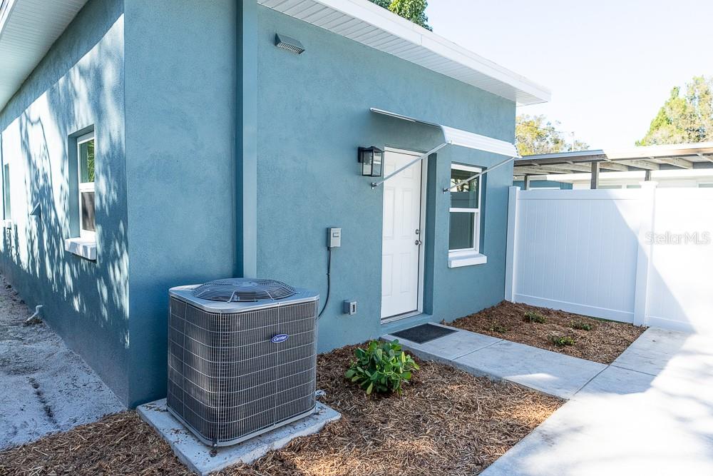 The exterior of a blue house features an HVAC unit, a white door, and a walkway — 3520 1/2 8TH AVENUE N, ST PETERSBURG, FL