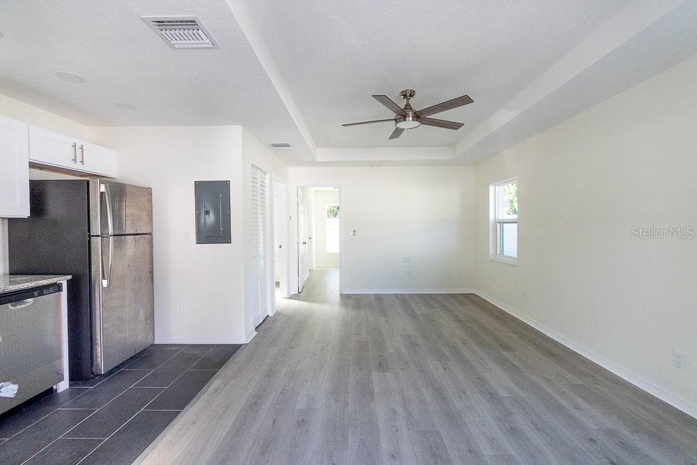 A kitchen with stainless steel appliances opens into a living area with wood-look flooring — 3520 1/2 8TH AVENUE N, ST PETERSBURG, FL