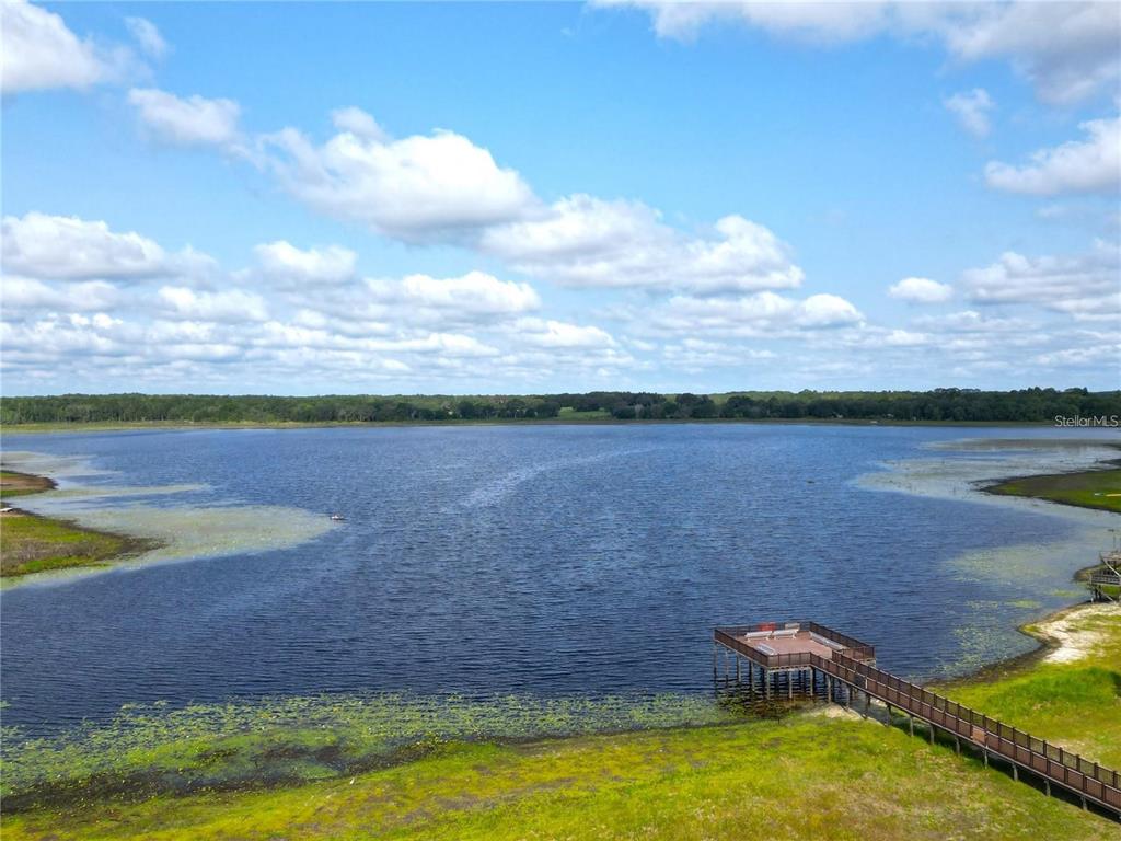 An aerial view of a lake with a wooden pier extending from the grassy shore — Lot 22 SW RAINBOW LAKES BOULEVARD, DUNNELLON, FL