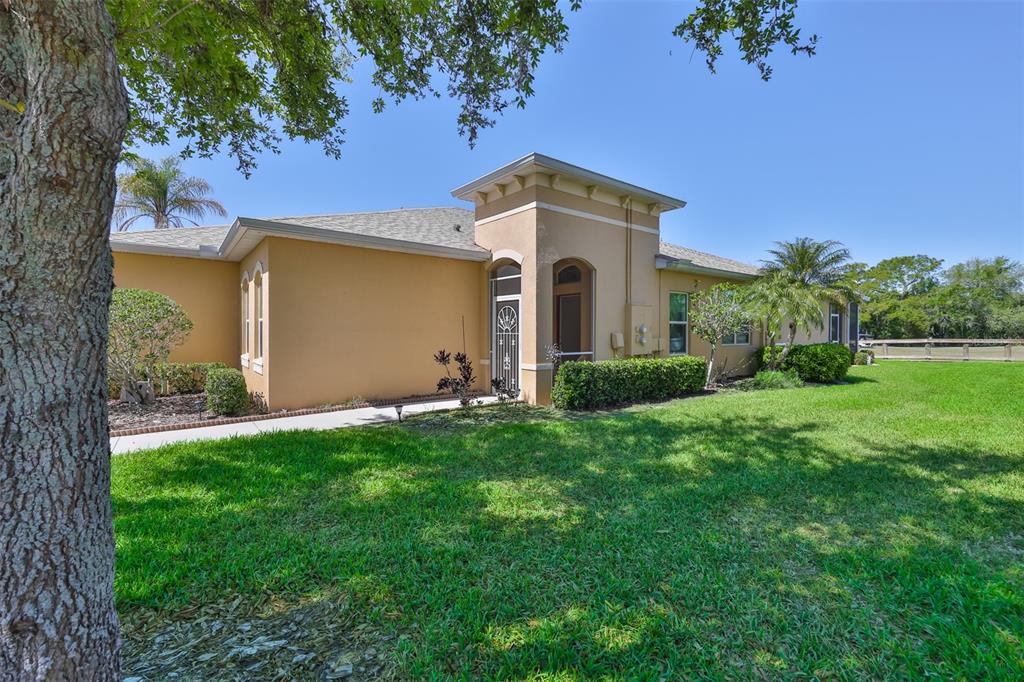 A tan single-story house with a prominent entryway and a large green lawn — 2423 RICHMOND GREENS COURT, SUN CITY CENTER, FL