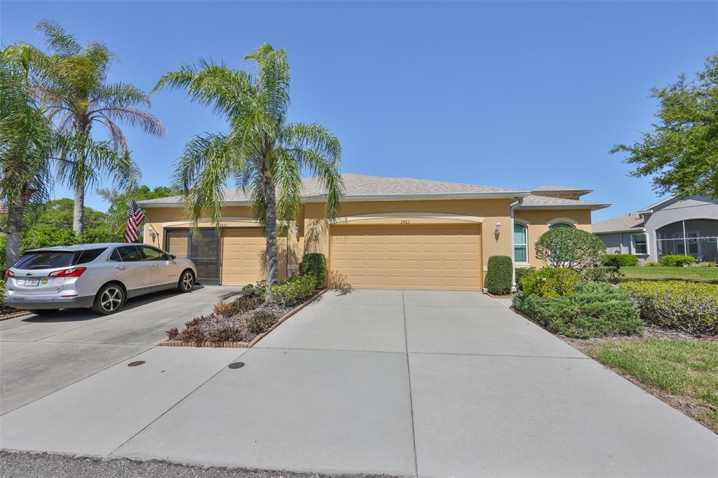 A single-story house with a tan exterior, a two-car garage, and a palm tree — 2423 RICHMOND GREENS COURT, SUN CITY CENTER, FL