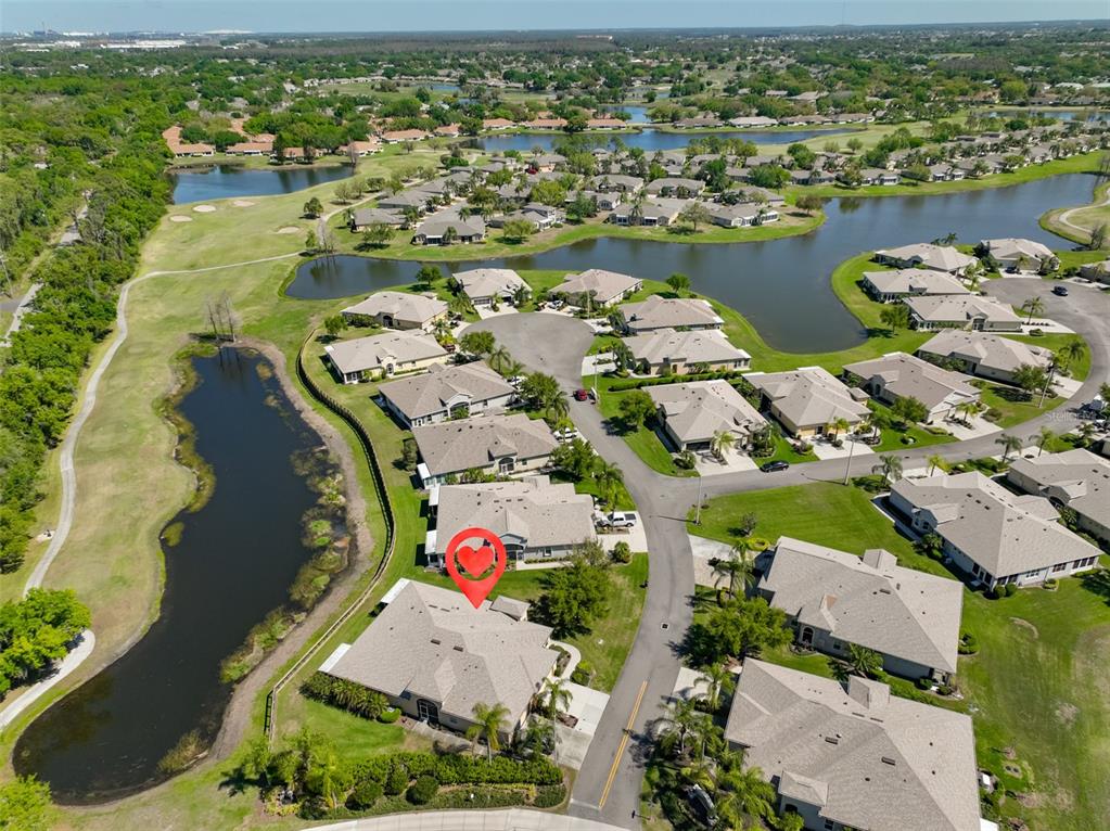 An aerial view shows a residential neighborhood with houses surrounding a lake and golf course — 2423 RICHMOND GREENS COURT, SUN CITY CENTER, FL