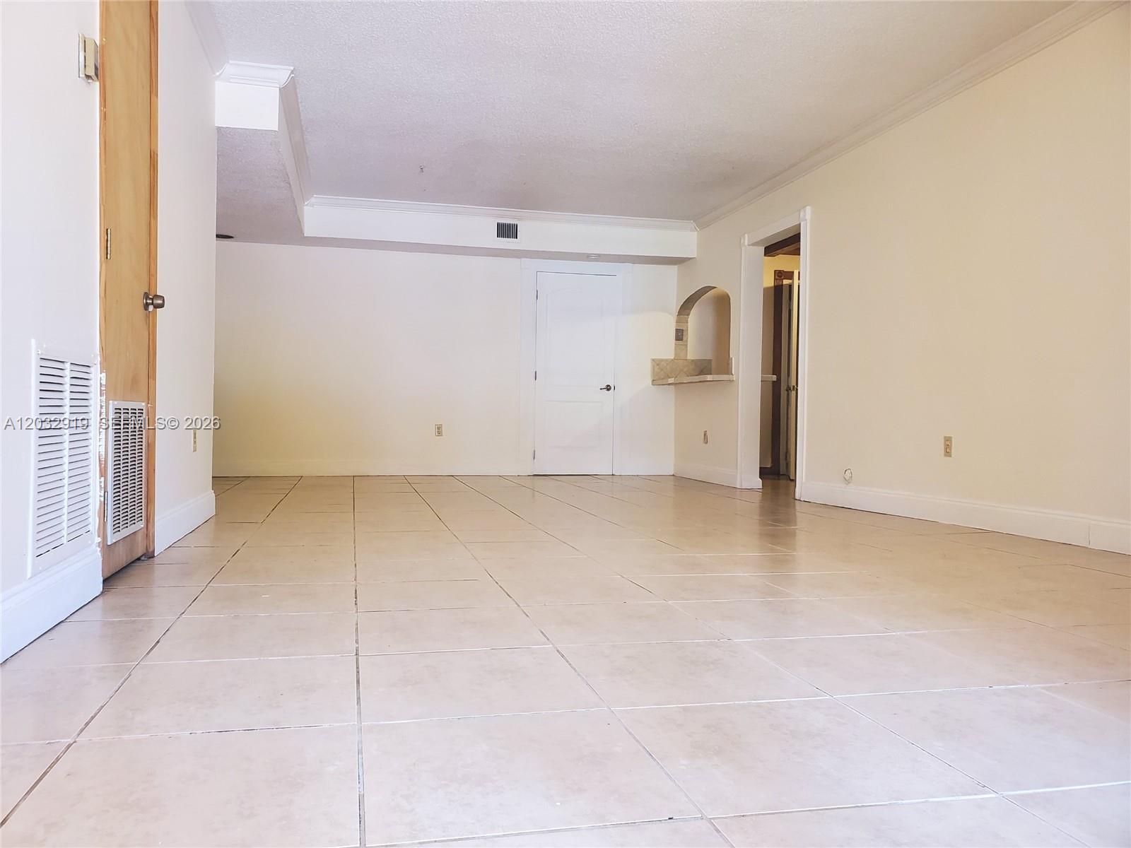 An empty room features beige tile flooring, white walls, a white door, and a small alcove — 250 NW 107th Ave # 106, Miami FL 33172, MIAMI, FL