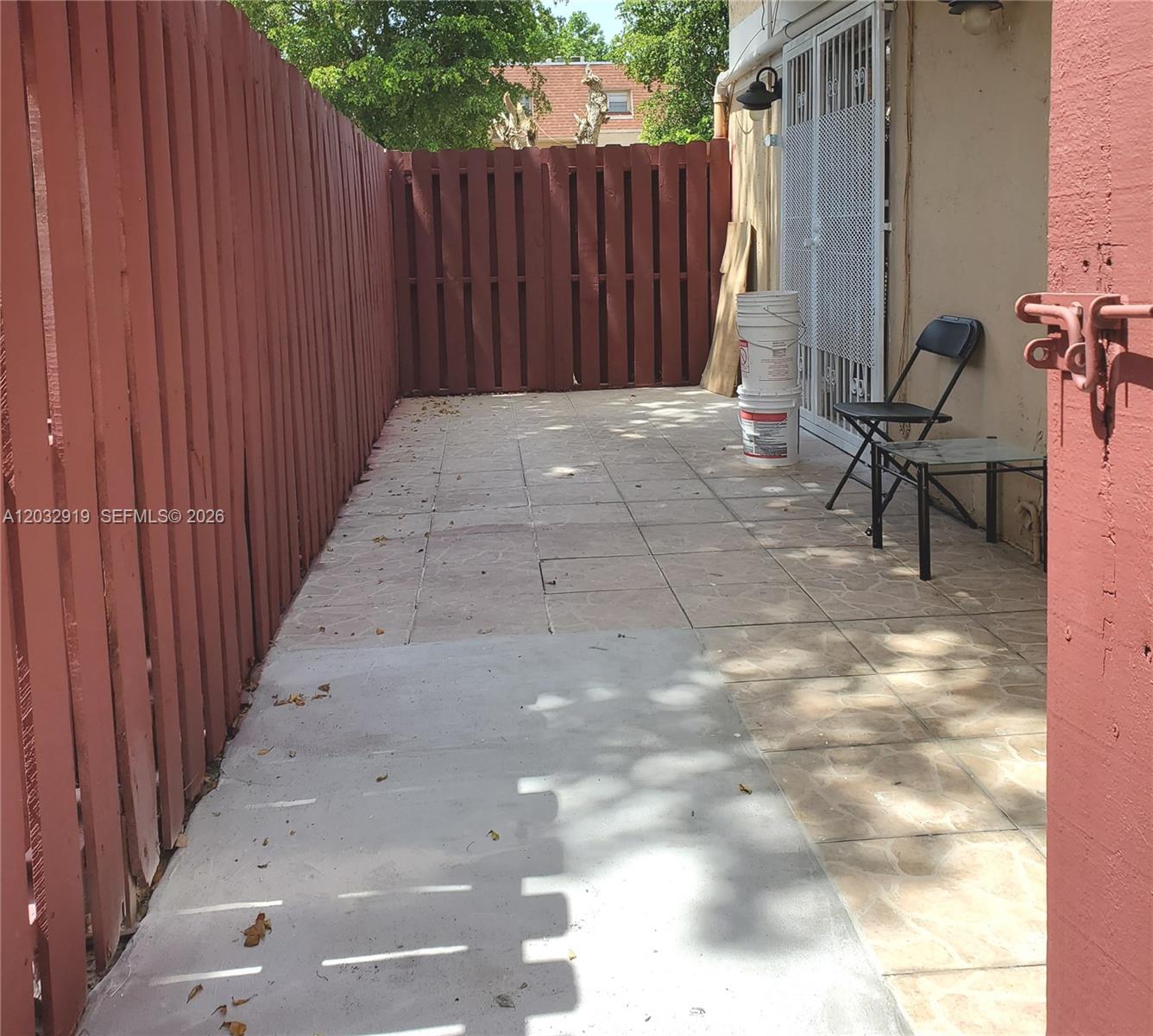 A fenced-in patio area features tiled flooring, a concrete section, and a small metal table — 250 NW 107th Ave # 106, Miami FL 33172, MIAMI, FL