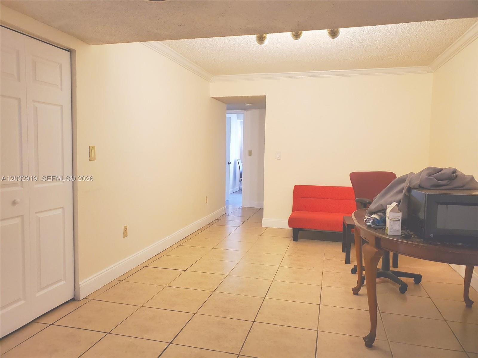 A room with beige tile flooring, a white door, and a red sofa — 250 NW 107th Ave # 106, Miami FL 33172, MIAMI, FL