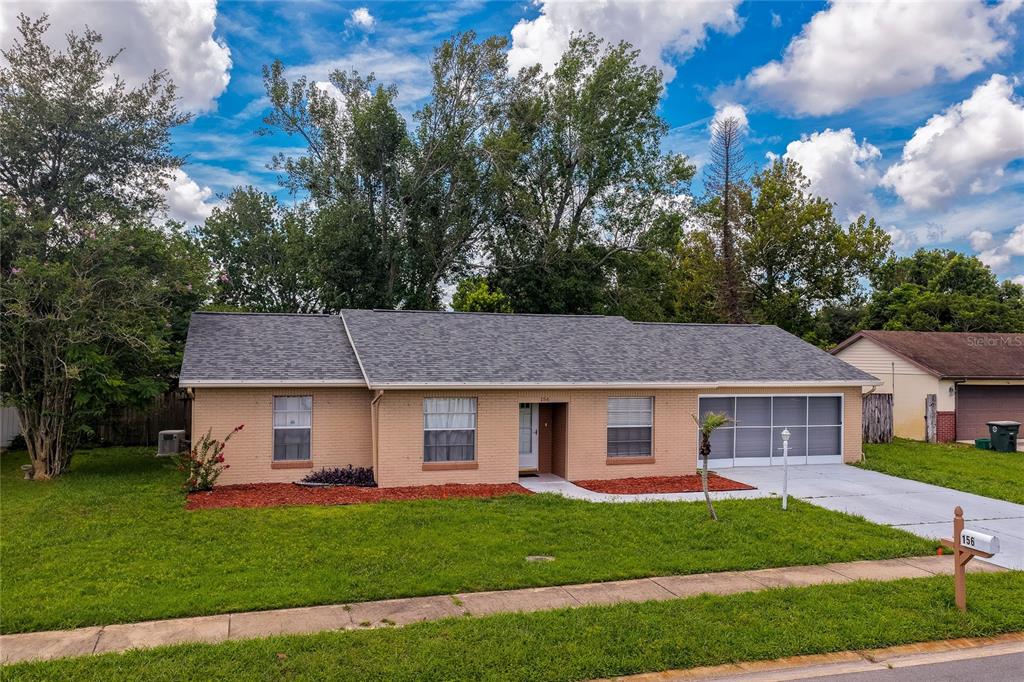 A single-story brick house with a gray shingled roof and a screened-in garage — 156 SPRINGWOOD DRIVE, DAYTONA BEACH, FL