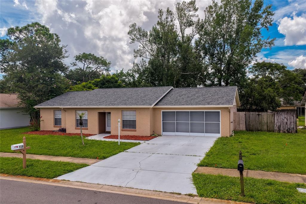 A single-story brick house with a gray shingled roof and a screened-in garage — 156 SPRINGWOOD DRIVE, DAYTONA BEACH, FL