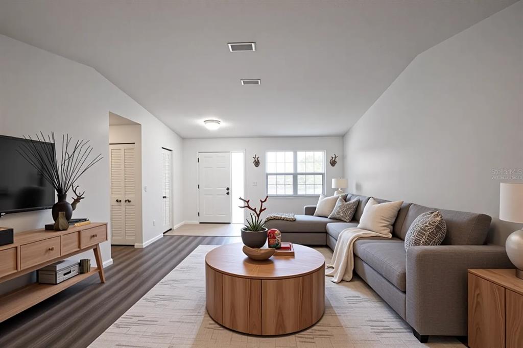 A living room with gray sectional seating, a round wooden coffee table, and wood-look flooring — 13 WHITTINGTON DRIVE, PALM COAST, FL