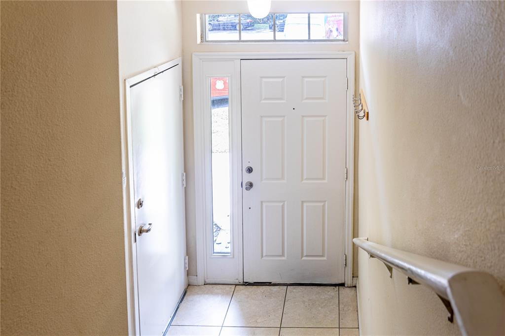An entryway features a white front door with a sidelight, tile flooring, and a staircase — 6438 S GOLDENROD ROAD UNIT 19A, ORLANDO, FL