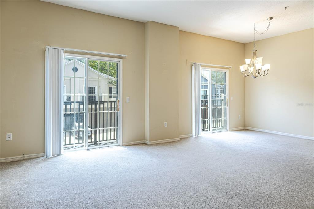A carpeted dining area features two sliding glass doors and a hanging chandelier — 6438 S GOLDENROD ROAD UNIT 19A, ORLANDO, FL