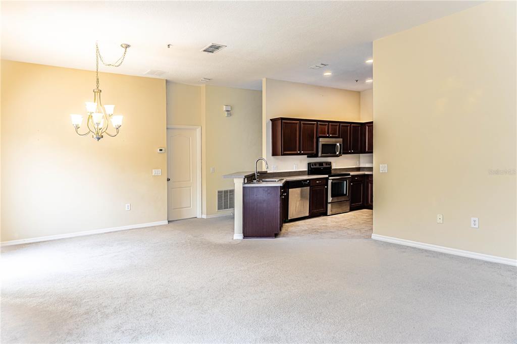 A dining area with a chandelier opens into a kitchen featuring dark wood cabinets — 6438 S GOLDENROD ROAD UNIT 19A, ORLANDO, FL