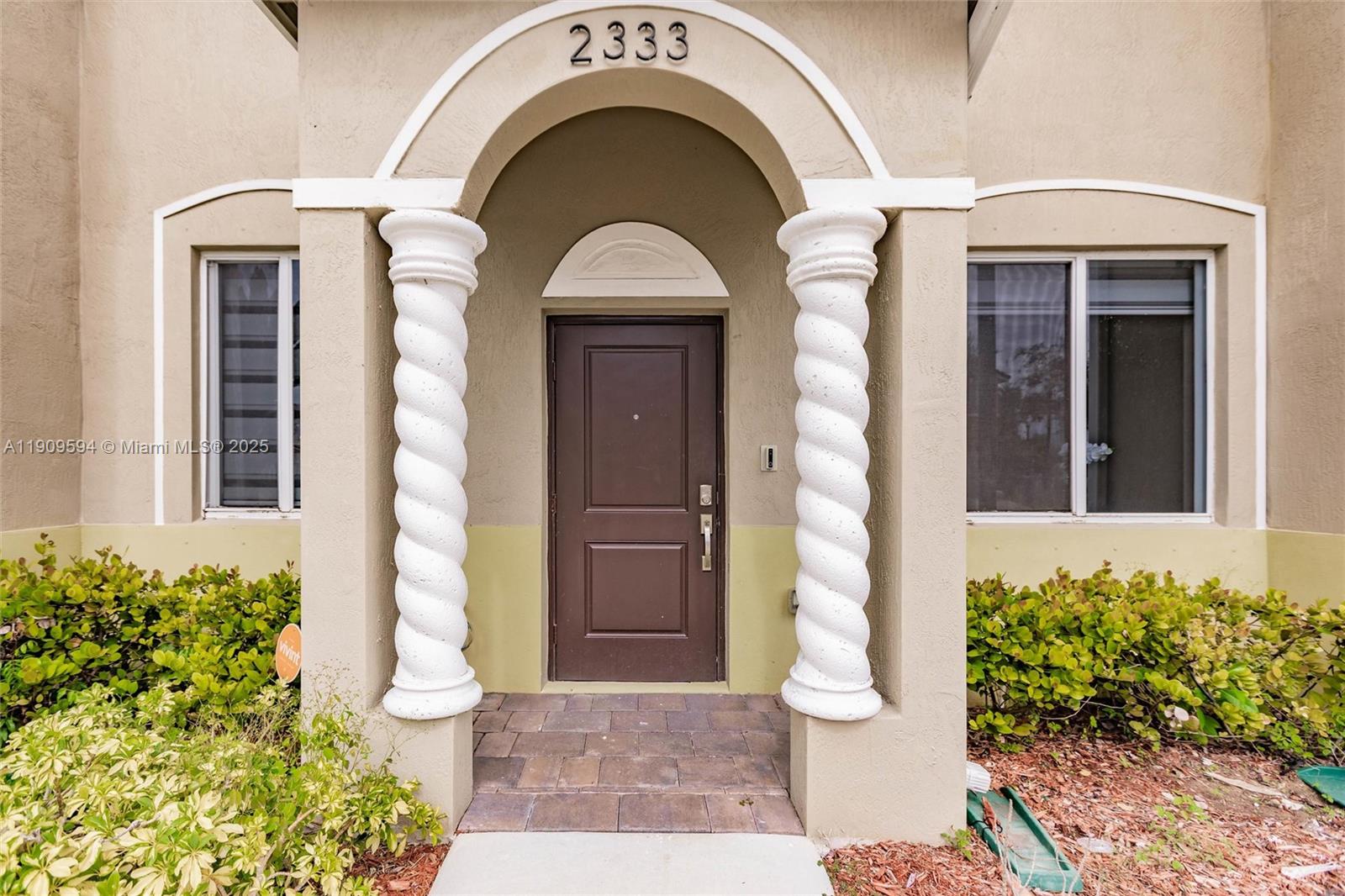 The front entrance features a brown door flanked by two white spiral columns — 2333 SE 10th St, Homestead FL 33035, HOMESTEAD, FL