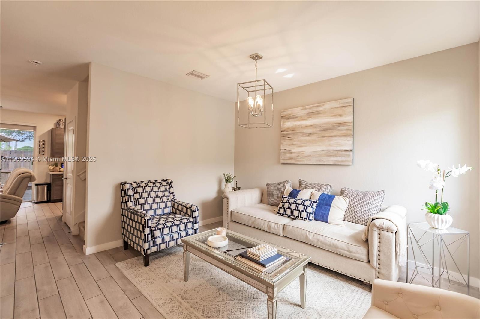A living room features a beige sofa, a patterned armchair, and a mirrored coffee table — 2333 SE 10th St, Homestead FL 33035, HOMESTEAD, FL