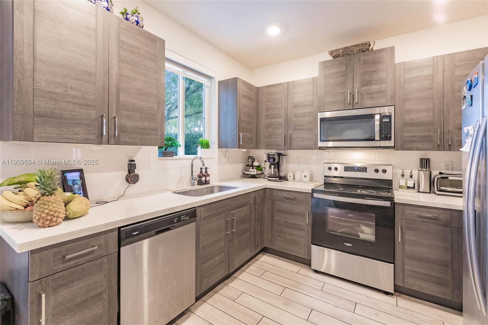 A kitchen features gray wood-grain cabinets, stainless steel appliances, and white quartz countertops — 2333 SE 10th St, Homestead FL 33035, HOMESTEAD, FL