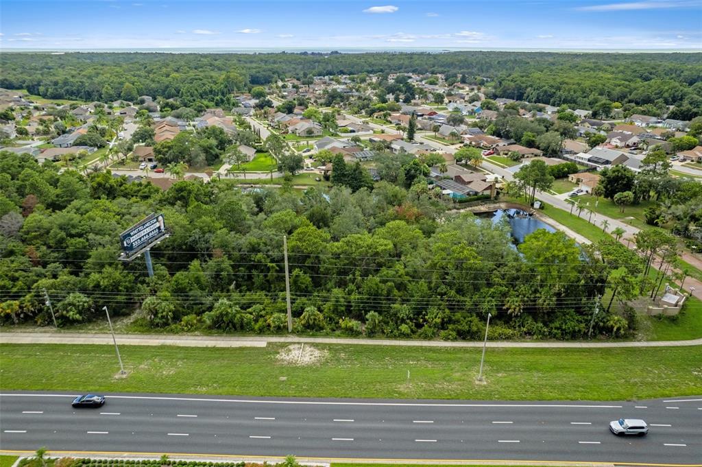 An aerial view shows a wooded lot situated between a highway and a residential neighborhood — 00 US HWY 19, HUDSON, FL
