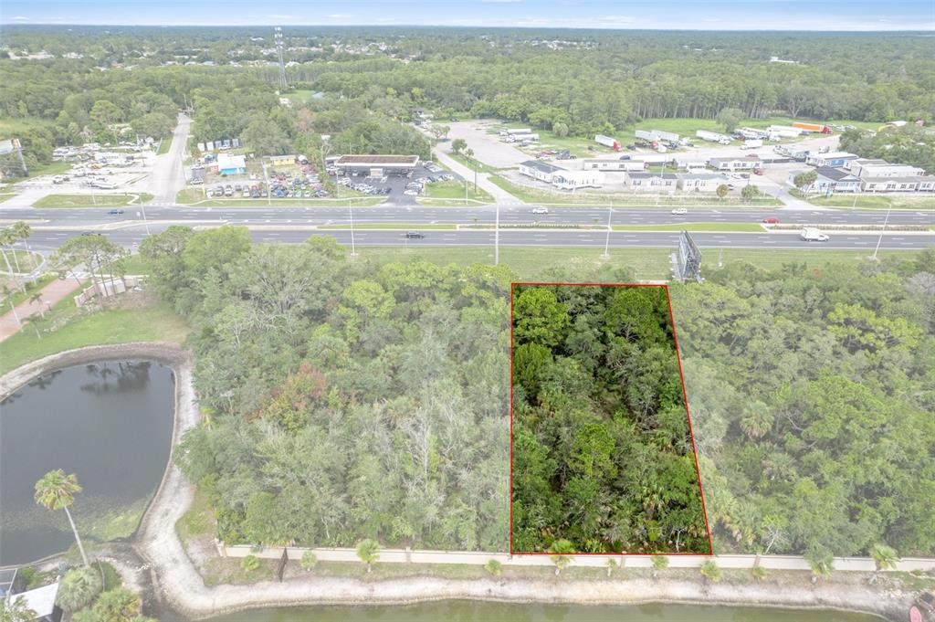 An aerial view shows a rectangular, wooded lot outlined in red near a highway — 00 US HWY 19, HUDSON, FL